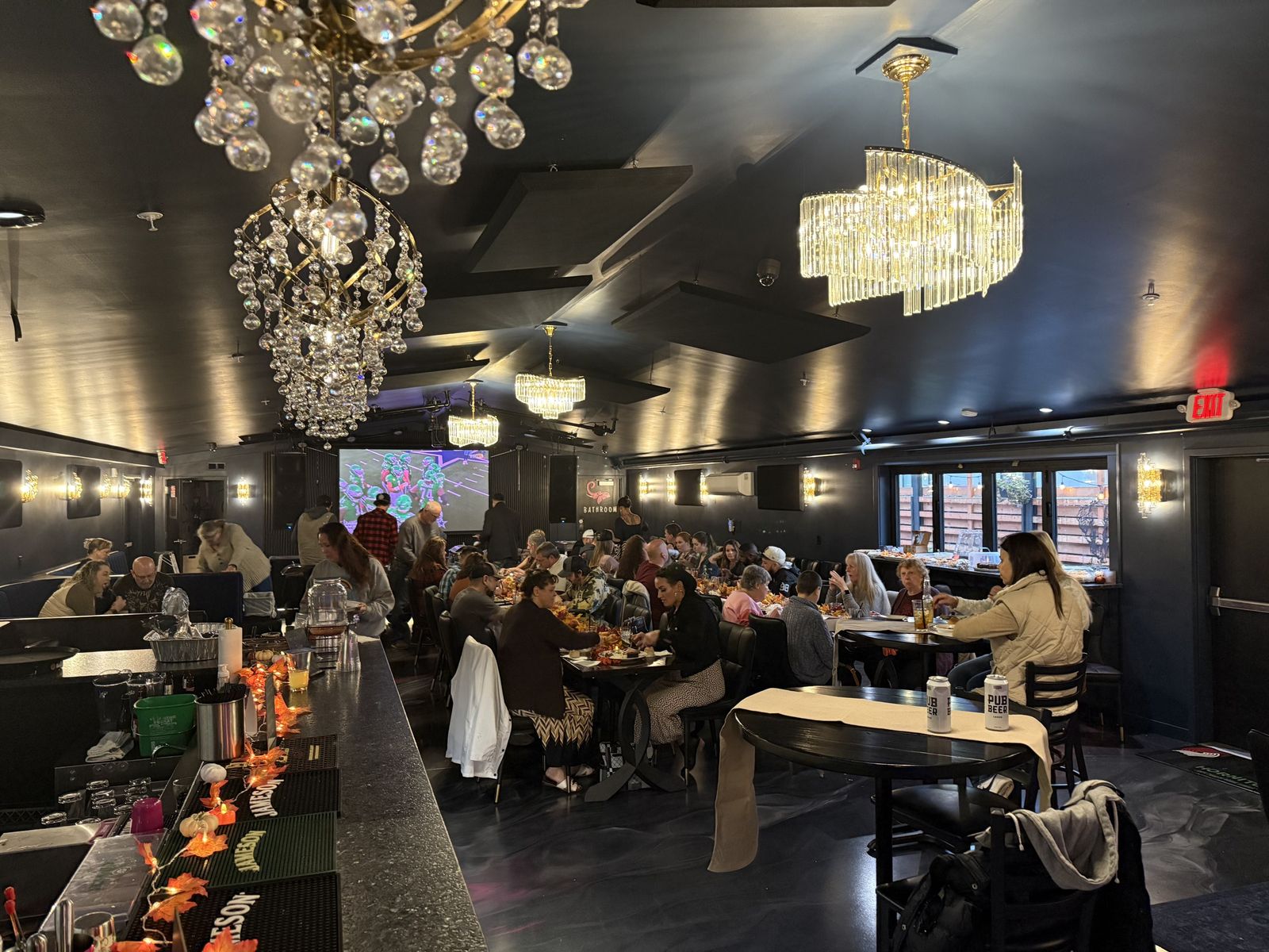 The dining room at The Pink Elephant with chandeliers and a full house